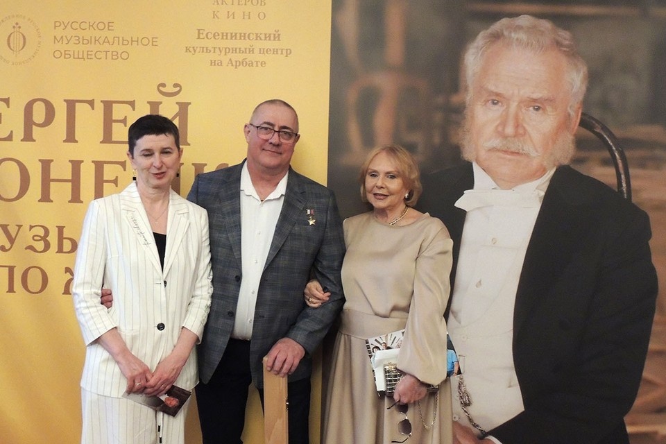    На фоне портрета Сергея Никоненко его жена Екатерина Воронина и герой России Сергей Петров с супругой. Анастасия ПЛЕШАКОВА