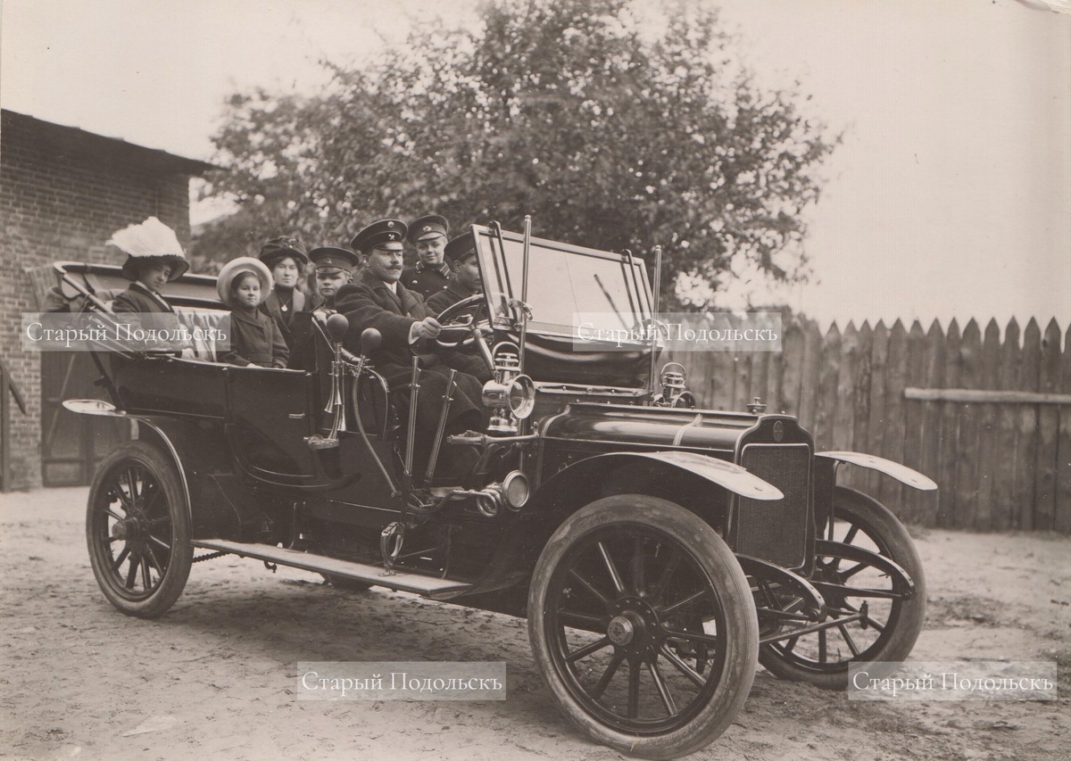    Подольск, 1910 г., с территории Цементного завода выезжает семья Доллежалей, слева направо: Елена Фердинандовна (сестра главного инженера завода); Оля (дочь главного инженера и сестра будущего знаменитого ученого-энергетика); гувернантка семьи (француженка); Володя (сын главного инженера и брат знаменитого ученого-энергетика, сам будущий инженер-конструктор авиационных моторов); Антон Фердинандович (главный инженер Подольского цементного завода); Коля (будущий знаменитый ученый-энергетик); помощник семьи. Это один из первых автомобилей на улицах Подольска. Фотография публикуется впервые. / Из коллекции Александра Семенихина, автора проекта "Старый Подольскъ".