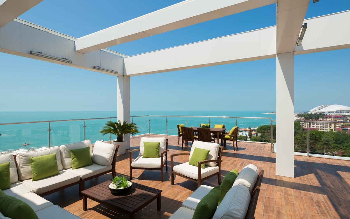 Панорамная терраса с видом на Черное море в Radisson Collection Paradise Resort & SPA 5* на улице 65 лет Победы, 50. Отель расположен на первой береговой линии в Сириусе, на абсолютно плоском рельефе Имеретинской низменности. В 2026 году это одна из самых востребованных локаций для премиального отдыха благодаря огромному SPA-комплексу, открытым бассейнам и близости к Олимпийскому парку.
