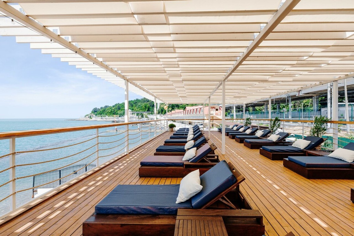 Терраса на собственном оборудованном пляже отеля Marine Garden Sochi by Zont Hotel Group 5* на Шоссейной улице, 9, корпус 1. Гостиничный комплекс располагает благоустроенной парковой зоной площадью более одного гектара и современным спа-центром с термальной зоной и открытым подогреваемым бассейном. В 2026 году этот объект остается актуальным для планирования отдыха благодаря развитой детской анимации и возможности совместить тихий отдых в Хосте с близостью к ключевым локациям Большого Сочи.