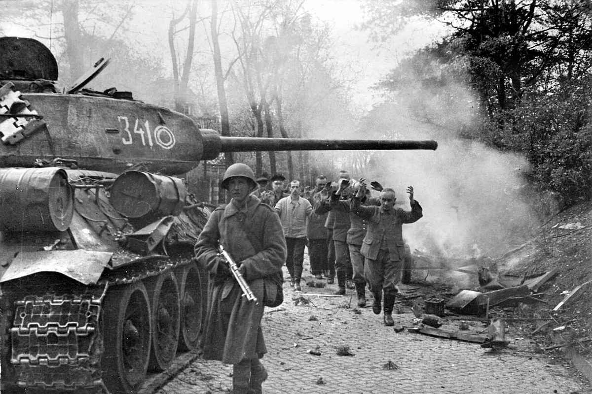 Танк Т-34-85 из 7-го гвардейского танкового корпуса и пленные немецкие ополченцы из фольксштурма на улицах Берлина.