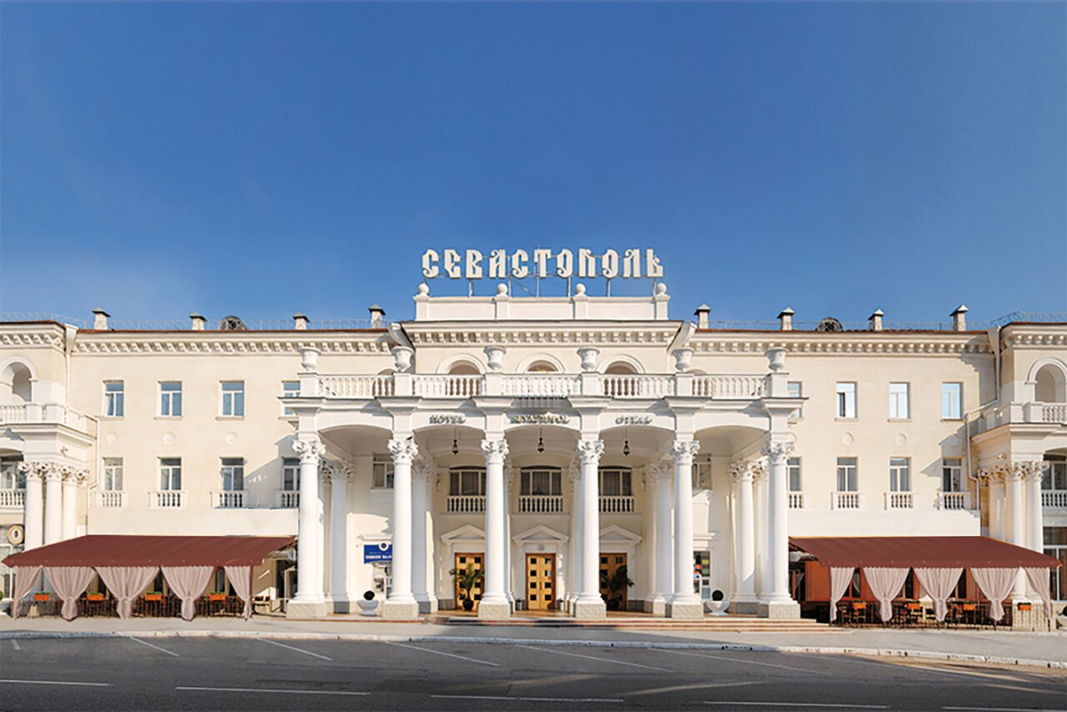 Фасад отеля «Севастополь» 3* на проспекте Нахимова, 8 в Севастополе. Здание, построенное в 1952 году в стиле неоклассицизма, является памятником архитектуры и обеспечивает гостям прямой доступ к Приморскому бульвару и Артиллерийской бухте. В 2026 году это подходящая локация для планирования тихого отдыха в историческом центре с возможностью посещения собственного SPA-центра и панорамного ресторана.