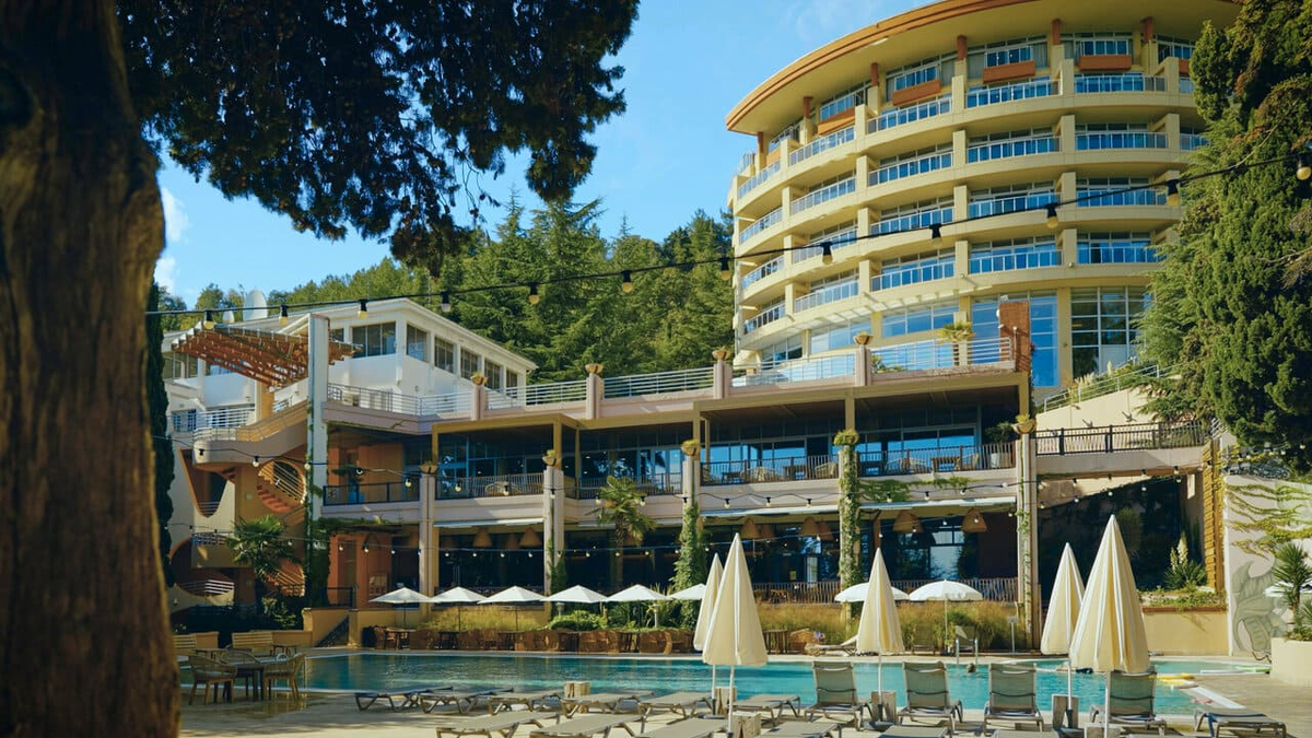Фасад девятиэтажного SPA-корпуса и открытый бассейн отеля More Spa & Resort 5* на улице Набережной, 25 в Алуште. Расположение медицинского центра непосредственно в здании виллы позволяет гостям проходить оздоровительные процедуры, не покидая жилую зону комплекса. В 2026 году это востребованная локация для планирования восстановительного отдыха в окружении реликтового парка Профессорского уголка.