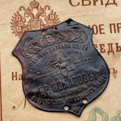 Металлические этикетки Комаровской фабрики пришивались к валенку на две точки фиксации. И при желании их можно было легко снять, поддев ножницами нитки прошивки. Но ярлык, как правило, оставляли - уж очень он был роскошен. Новым он ещё и блестел на манер золотого. Поскольку сами комаровские валенки были дорогими, симбиоз с лейблом получался очень органичным.