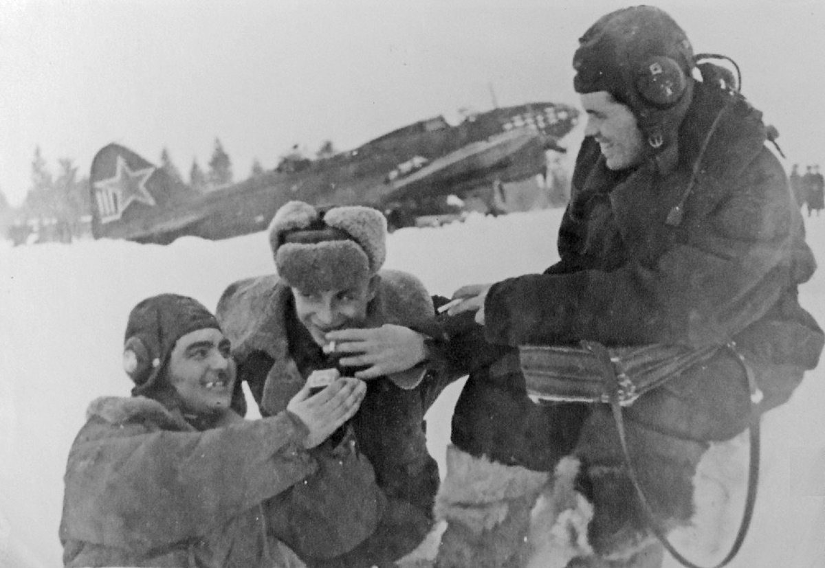 Советские летчики стрелок-радист старший сержант Малик Чарыев, пилот лейтенант Илья Мусатов и штурман капитан Артемий Торопов из 752-го авиационного полка дальнего действия курят на краю летного поля недалеко от стоянки своего бомбардировщика Ил-4. Воронежская область, аэродром Липецк, начало марта 1943 года.