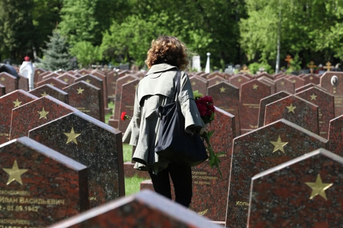    Женщина возлагает цветы на Воинском мемориале Преображенского кладбища Москвы.