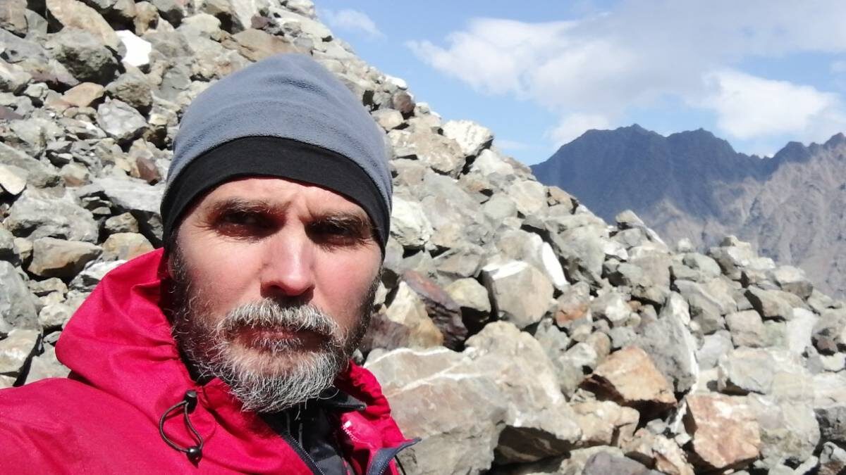    Гляциолог Роберт Чернов во время экспедиции к леднику Колка. За его спиной — морена, которая скрывает льды под слоем камней / Фото: Личный архив