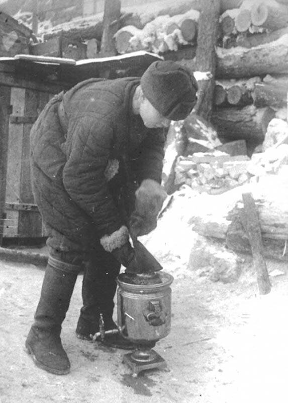 Боец раздувает самовар у блиндажа. Фотография Якова Рюмкина