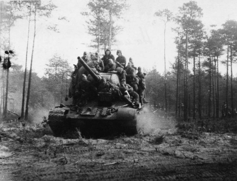Танк Т-34-85 63-й гвардейской танковой бригады с десантом движется по лесной дороге, 1944 год.