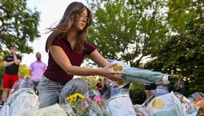 Женщина возлагает цветы на поминальной церемонии недалеко от места смертельной стрельбы в Университете штата Флорида в 2025 году