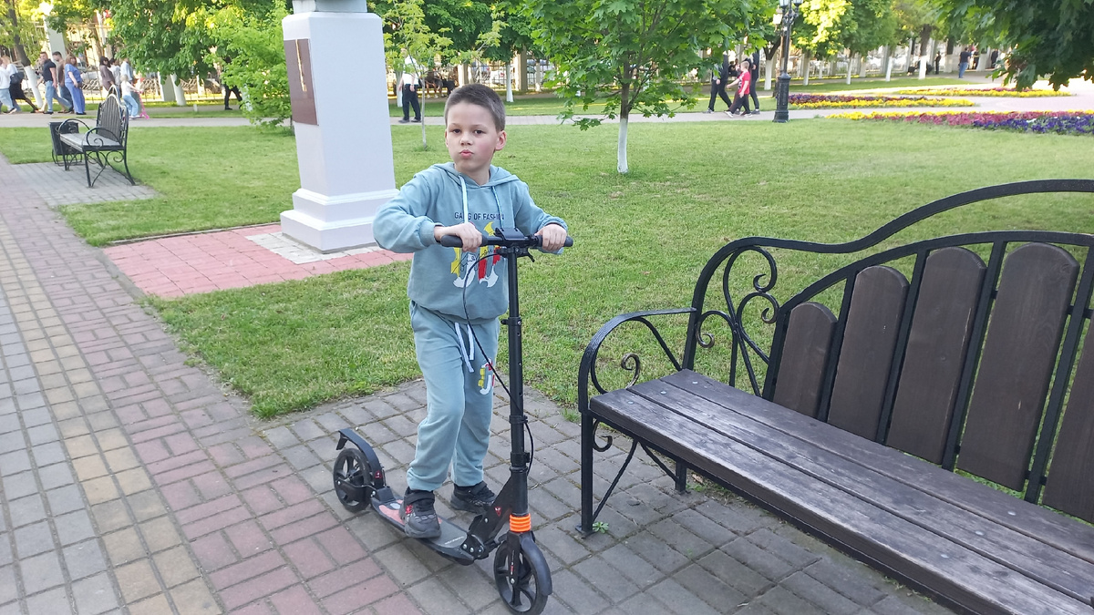 Сын на самокате в парке