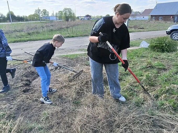 Дети и взрослые убирают граблями сухостой