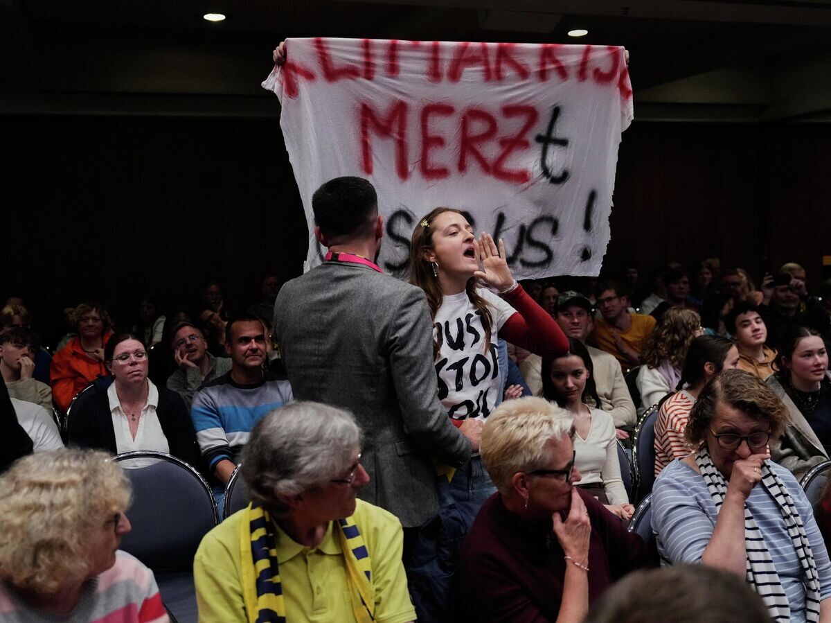    Девушка протестует во время выступления канцлера Германии Фридриха Мерца на Дне немецких католиков в Вюрцбурге | © AP Photo / Matthias Schrader