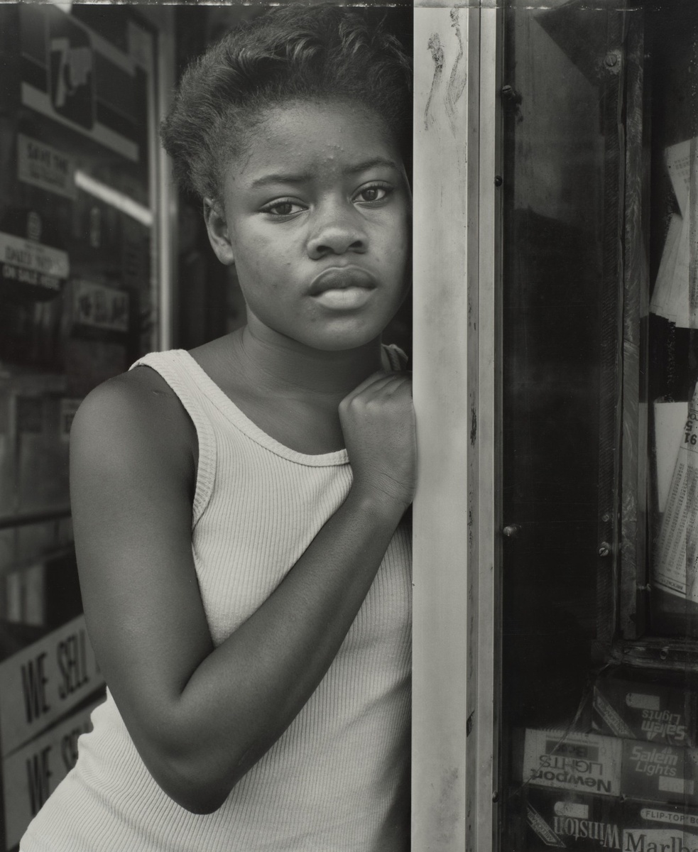 Dawoud Bey ─ A Girl in Deli Doorway, Brooklyn, NY, 1988