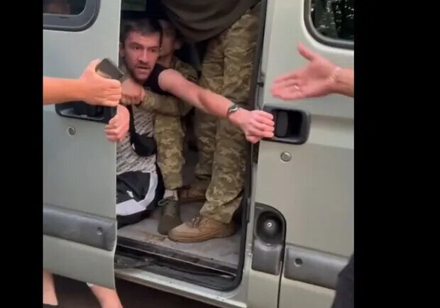 Очередной насильно мобилизованный мужчина на Украине - вырывается из автобуса, люди пытаются вытащить его из буса, протягивая ему руки.