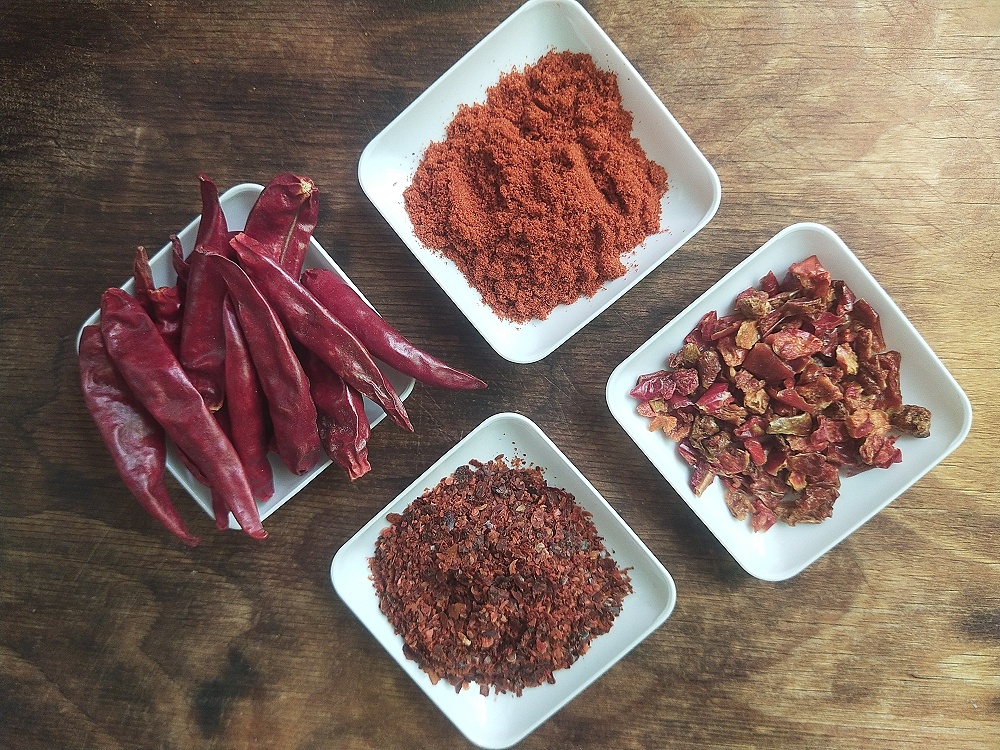 На фото представлены: целые стручки, крупные хлопья, мелкие хлопья и мелкий помол.