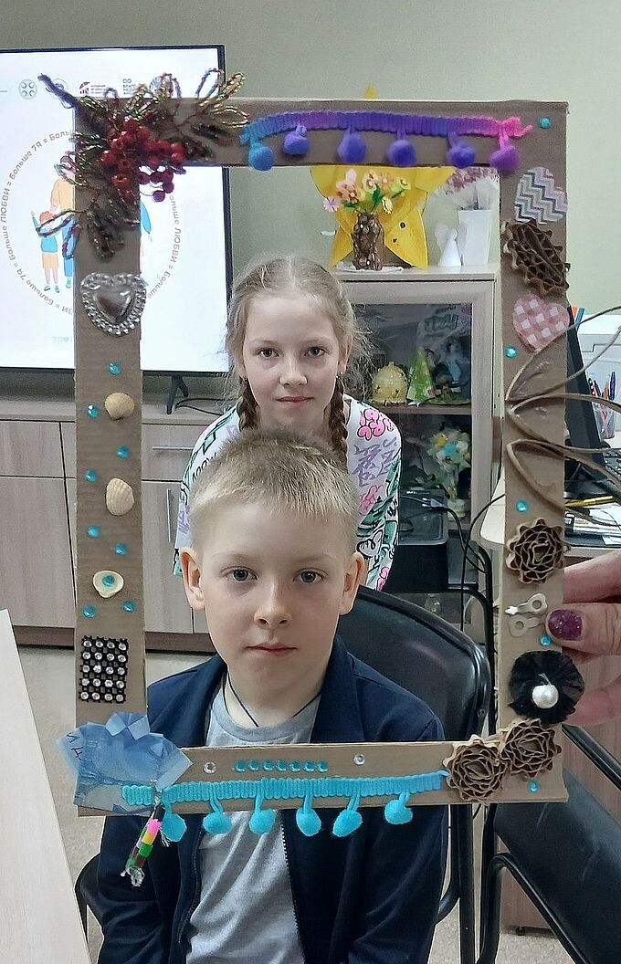 Мальчик и девочка смотрят через созданную ими фото-рамку