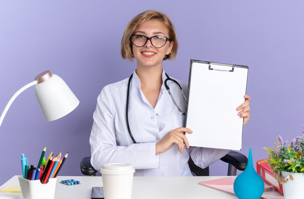 https://www.magnific.com/free-photo/smiling-young-female-doctor-wearing-medical-robe-with-stethoscope-glasses-sits-table-with-medical-tools-holding-clipboard-isolated-blue-background_17110029.htm