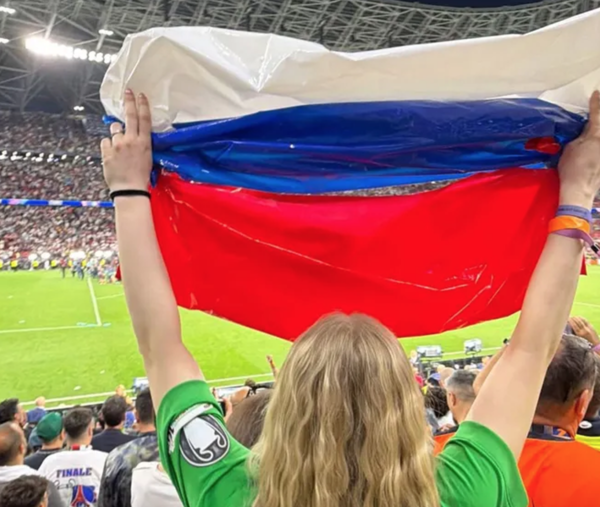    Марина Кондратюк, жена Матвея Сафонова, с самодельным флагом России на финале Лиги чемпионов. / соцсети Полины Лысенко