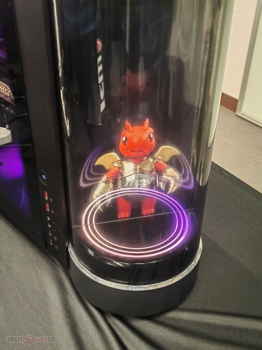    Red dragon figurine with gold wings inside a glossy black computer tower, illuminated by purple circular lights at the base.