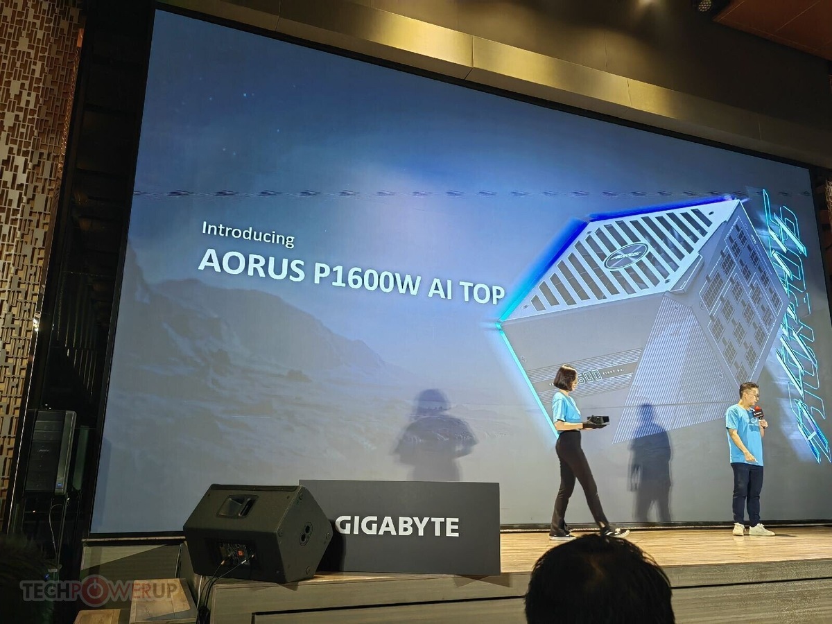    Stage presentation announcing AORUS P1600W AI TOP on a large screen; two hosts in blue shirts speak on stage with Gigabyte branding visible.