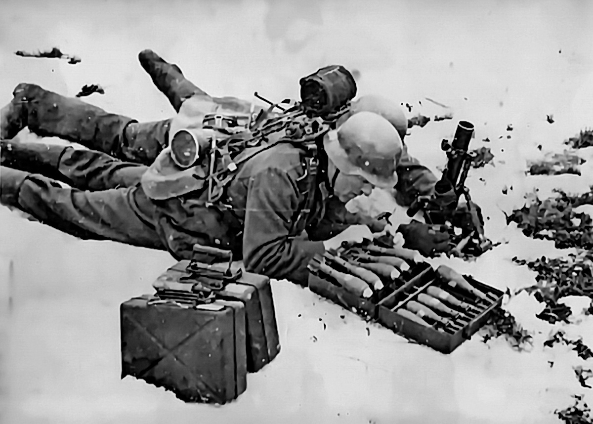 расчёт 50-мм миномёта G.W.36 изготовился к стрельбе зимой. Командир (наводчик) подравнивает миномёт, вращая рукоятки горизонтирующего механизма, на его спине видна катушка с кабелем для полевого телефона.