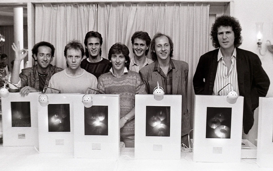 Группа Dire Straits позирует в 1985 году со своими наградами за самый продаваемый CD в Нидерландах. Слева направо: Джек Сонни, Алан Кларк, Крис Уайт, Терри Уильямс, Гай Флетчер, Марк Нопфлер и Джон Иллсли. Фото: Роб Верхорст/Redferns