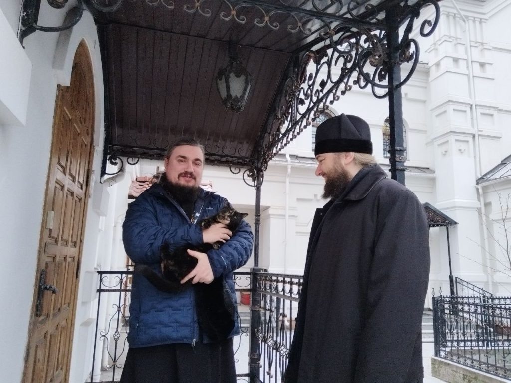 Отец Давид держит на руках кошку отца Саввы Анфиску