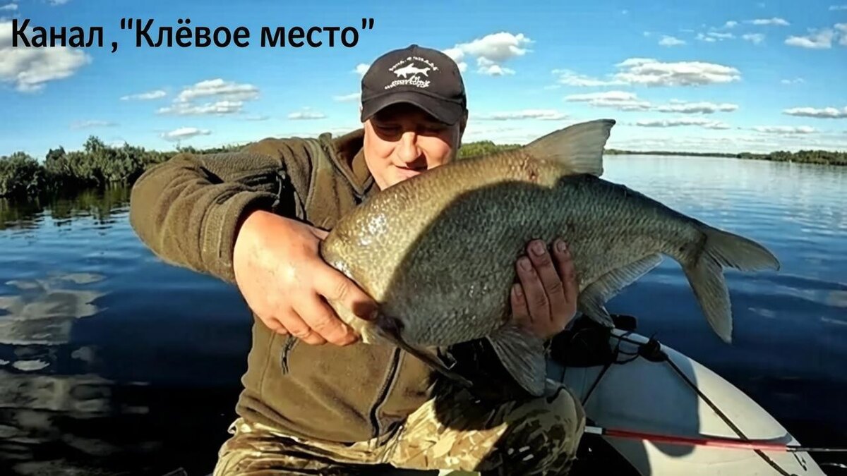 Рыболов в лодке на рассвете держит крупного леща над водой