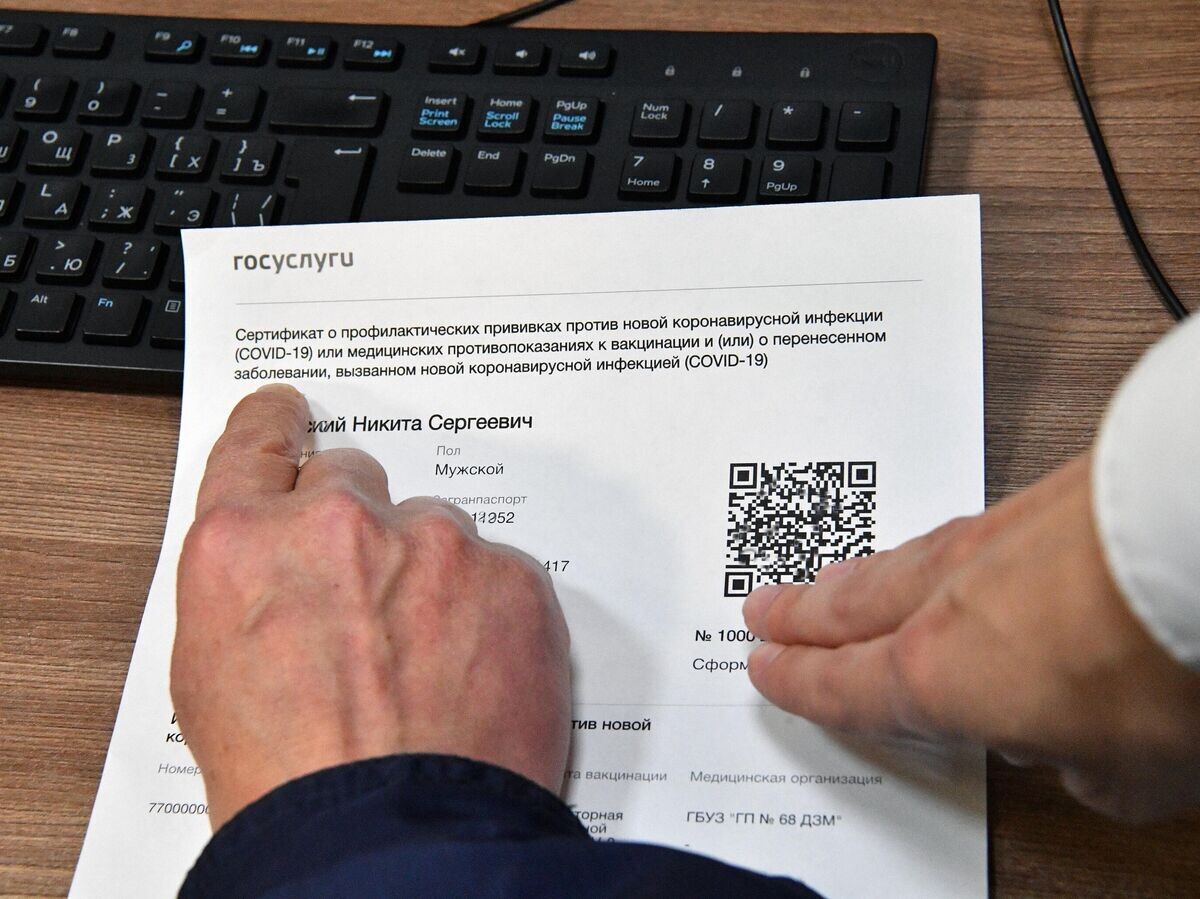    Посетитель осматривает распечатанный бумажный QR-код, полученный в многофункциональном центре госуслуг "Мои документы" в Москве | © РИА Новости / Алексей Куденко
