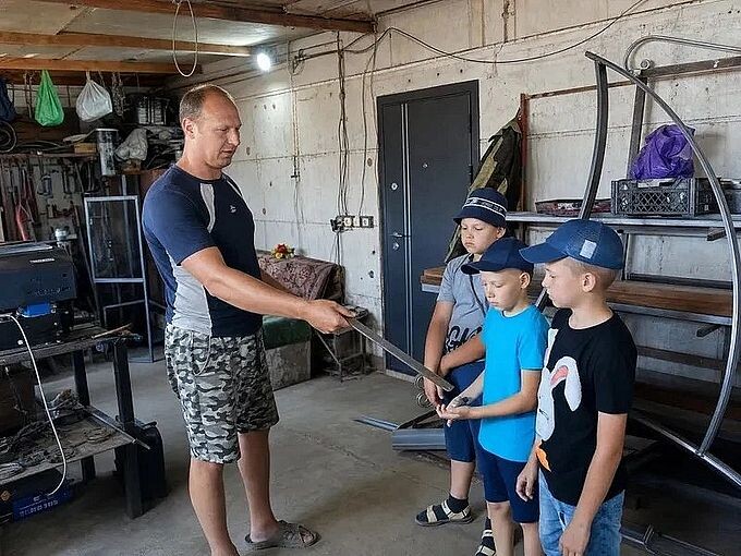 Питинов Юрий Сергеевич показывает детям металлическую заготовку