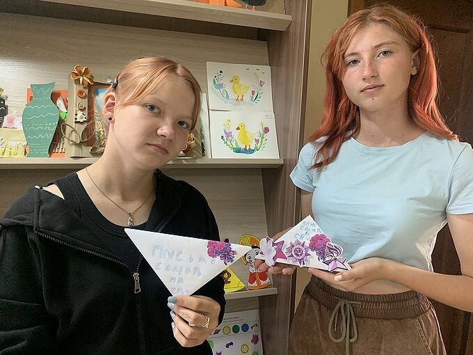 Две девочки-подростка держат в руках письма, свёрнутые треугольником