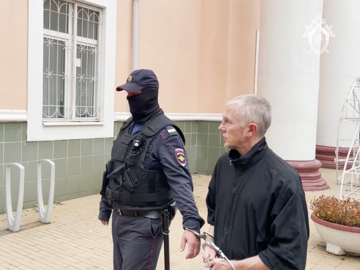    Мужчина, обвиненный в изнасилованиях и убийствах девушек 20-летней давности, в сопровождении сотрудника полиции | © Фото : Следком/Telegram