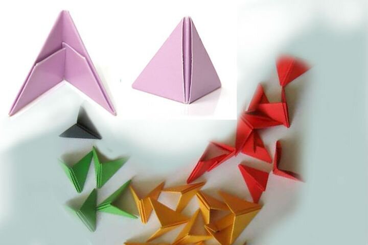 Что такое треугольный модуль В основе элемента лежит прямоугольник, размером от 1/4 до 1/36 альбомного листа (формат А4). Соединяются готовые модули за счёт выступающих «уголков» и глубоких «карманчиков», по принципу штекерного разъёма. Плотное прилегание деталей обеспечивает прочность конструкции, но для большей надёжности лучше дополнительно «посадить» их на клей.

Перед тем как делать треугольники для модульного оригами, необходимо нарезать прямоугольные заготовки определённого размера. Допустимо одновременное использование нескольких «калибров»: более крупного для основных объёмов и мелкого – для изящного декора. Разделить лист на модули можно, опираясь на базовую форму «Дверцы». Для самого ходового элемента 1/16 потребуется:

Сложить лист пополам в продольном направлении.
Раскрыть.
Каждую половинку сложить к центральной линии.
Раскрыть заготовку и повторить те же действия в поперечном направлении. В результате лист будет поделен на 16 частей, размером 7,4х5,3 см.
Получить 1/32 несколько сложнее. Лист А4 сначала в поперечном направлении делят вдоль центральной оси, а затем каждую половину складывают в четыре раза. Получается вдвое больше полос, чем в предыдущем случае. Для продольного направления действия те же, что и при разметке модуля 1/16. В результате образуются прямоугольники, размером 5,3х3,7 см. Нарезать заготовки лучше всего канцелярским ножом, подложив под лист доску, ДВП или специальный макетный коврик.
