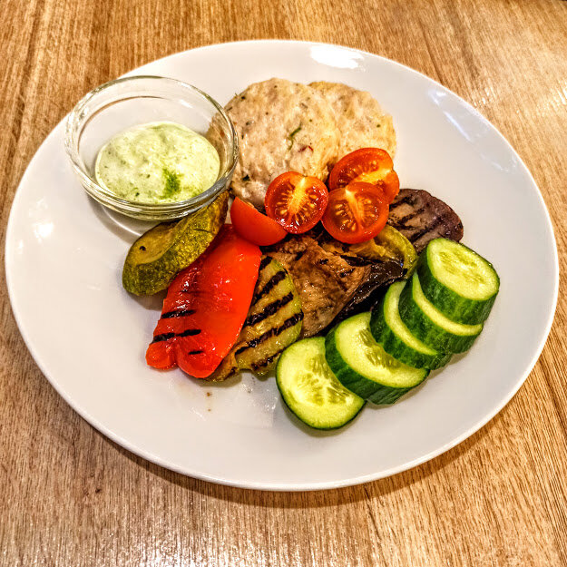 Еда, когда она происходит не дома: паровые куриные котлеты, куча овощей, соус из йогурта, чеснока и зелени.