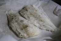 Для начала нужно просушить нежное филе салфеткой и убрать все косточки. Поперчить и слегка посолить заготовку с двух сторон. Выложить просоленные заготовки филе на силиконизированный пергамент, покрытый маслом.