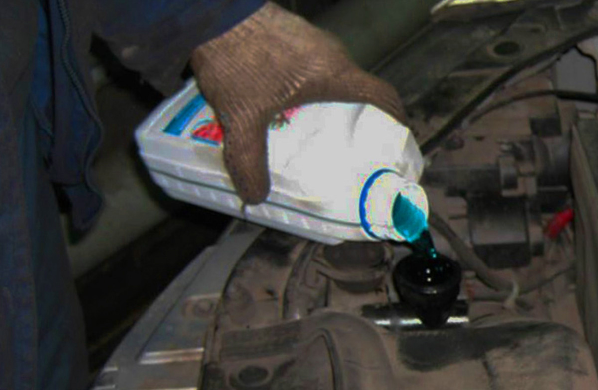 На фото изображен процесс залива охлаждающей жидкости в систему охлаждения автомобиля.