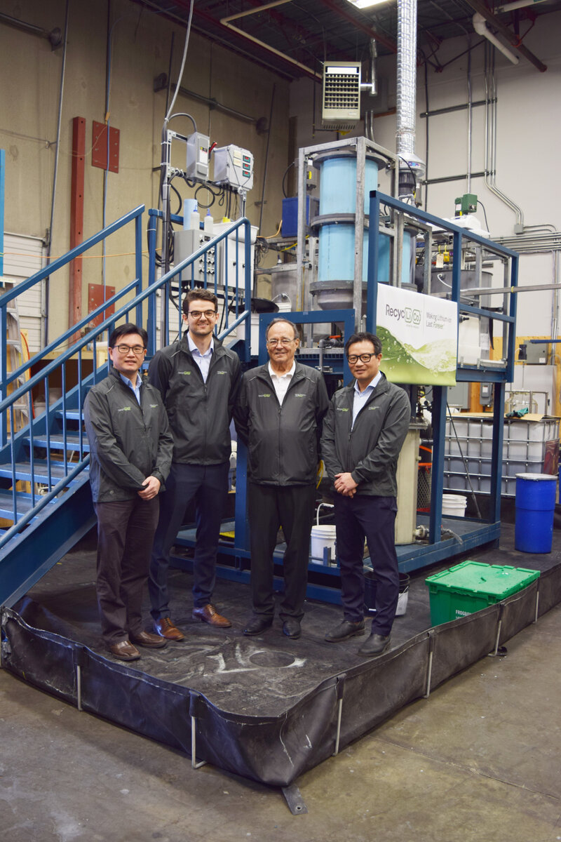 Генеральный директор American Manganese  Ларри Ро (второй справа) и ее технический директор Зарко Месельдзия  (третий справа) позируют фотографу перед системой утилизации  аккумуляторов компании (American Manganese)
