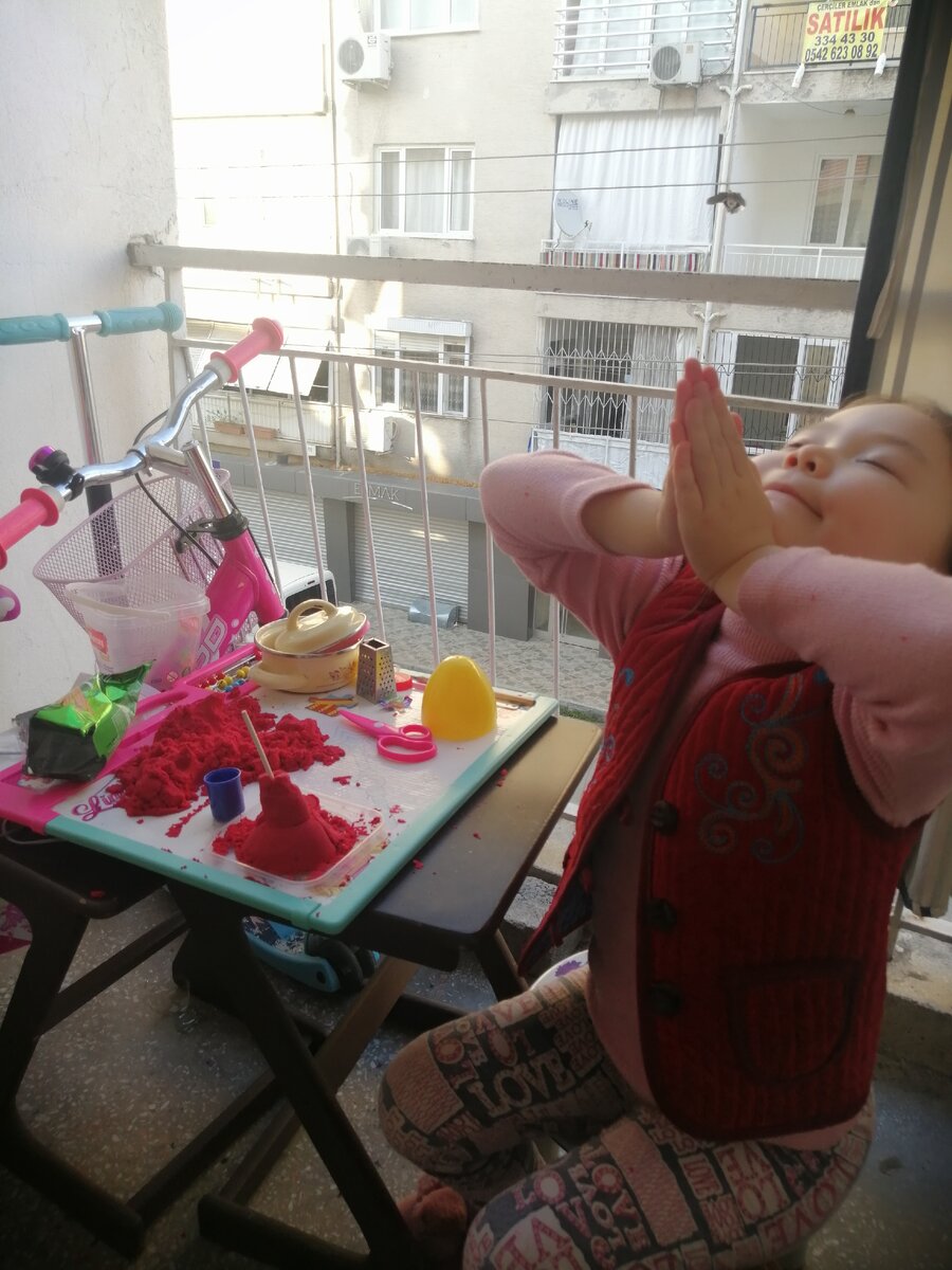 Доча довольная  играется на балконе. 