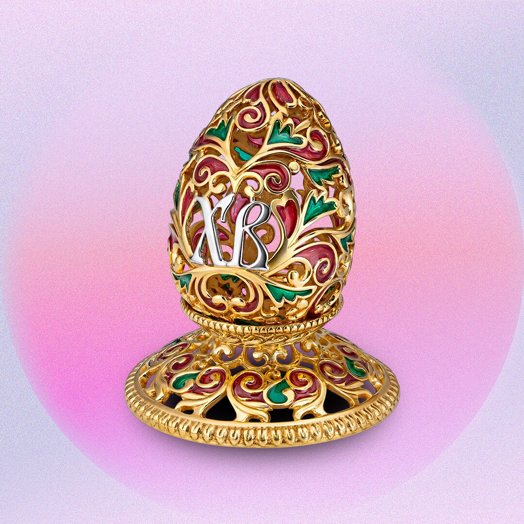 Серебряная "Подставка под яйцо" с символами праздника украсит торжественную сервировку стола, а также станет достойным подарком. Красота в деталях и эксклюзивный держатель яйца подарит вам настоящее эстетическое удовольствие, а также подчеркнет статус хозяйки. Использование подставки для яйца во время еды- это требование этикета. Яйцо выполнено в технике золочение. Изящные узоры драгоценного металла переплетаются в узоры, которые дополнены вставками рубиновой и изумрудной эмали, расписанными вручную лучшими эмальерами ювелирного дома RODIS.