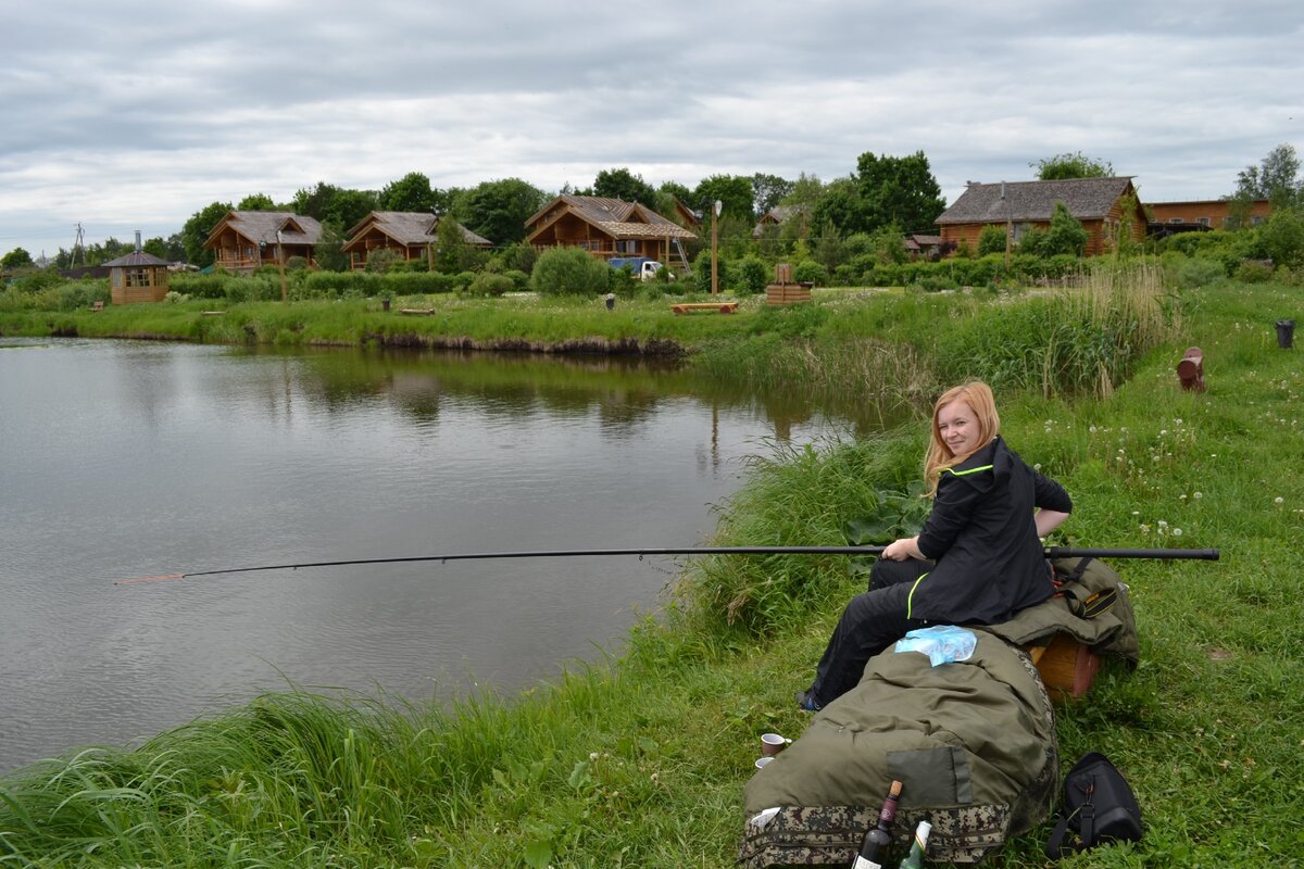 Зеленая территория с деревянными домиками, здесь же небольшой пруд