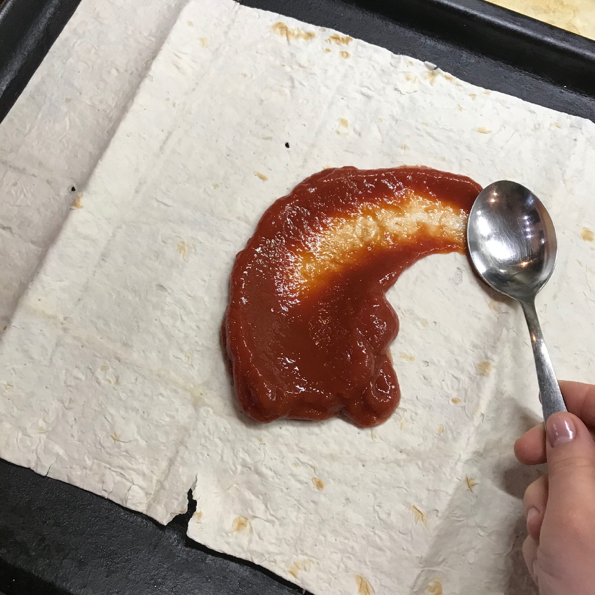 Томатную пасту тонким слоем наносим на лаваш