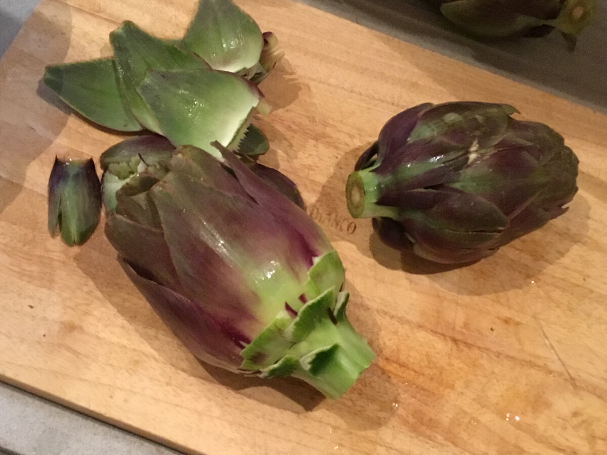 Сначала отрежем у артишока ножку, но не выбросим! Просто отложим в сторону. Затем просто оторвем два-три ряда наружных лепестков. 