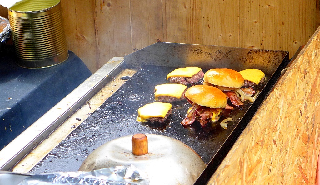 Бургеры с беконом и сыром, готовящиеся на непонятной чистоты панели.