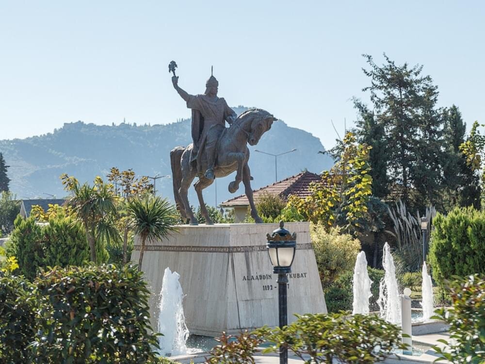 Конный памятник Кейкубату на фоне исторического полуострова с крепостью. Находится на въезде в Аланию.