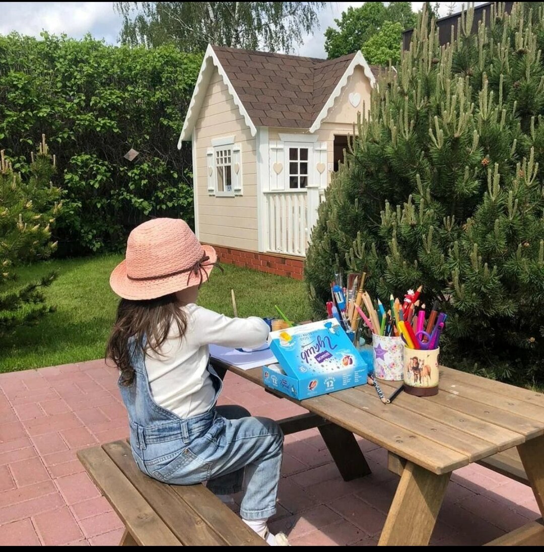 Юная хозяйка занимается творчеством рядом со своим домиком 