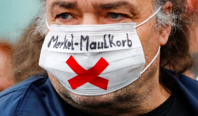 Демонстрант носит маску с надписью "морда Меркель"
