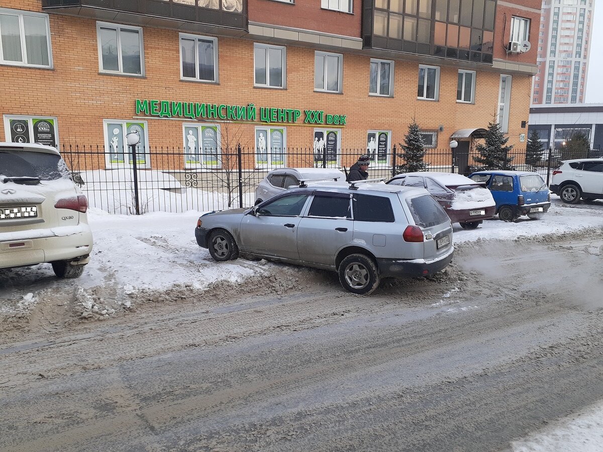 Эта легковушка застряла при выезде из парковочного кармана. Виной тому низкий дорожный просвет. Хозяин автомобиля в поисках спасителя. 