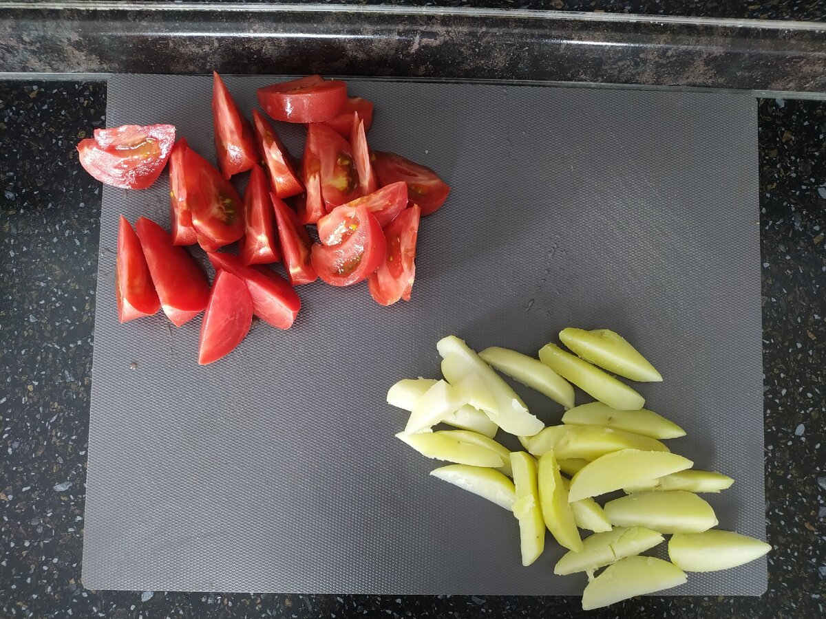 Картофель очистить и отварить до готовности. Затем слить воду и остудить при комнатной температуре. Нарезать на дольки. Помидоры вымыть и нарезать дольками.