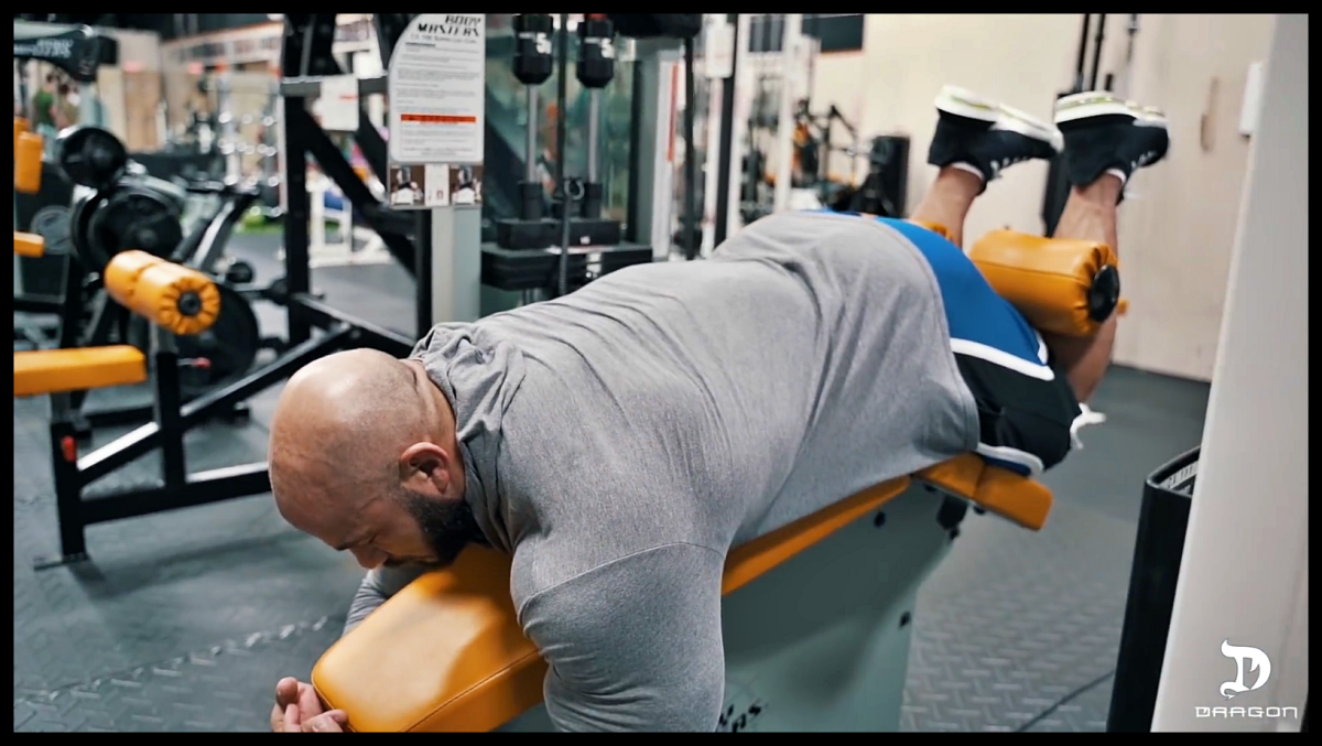 Сгибание ног лёжа в тренажёре. Скриншот из видео YouTube-канала: Dragon Pharma